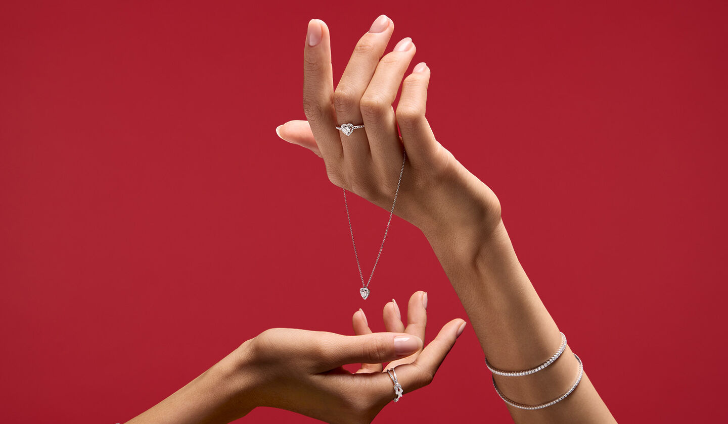 A woman holding Maison Birks jewellery on red background.